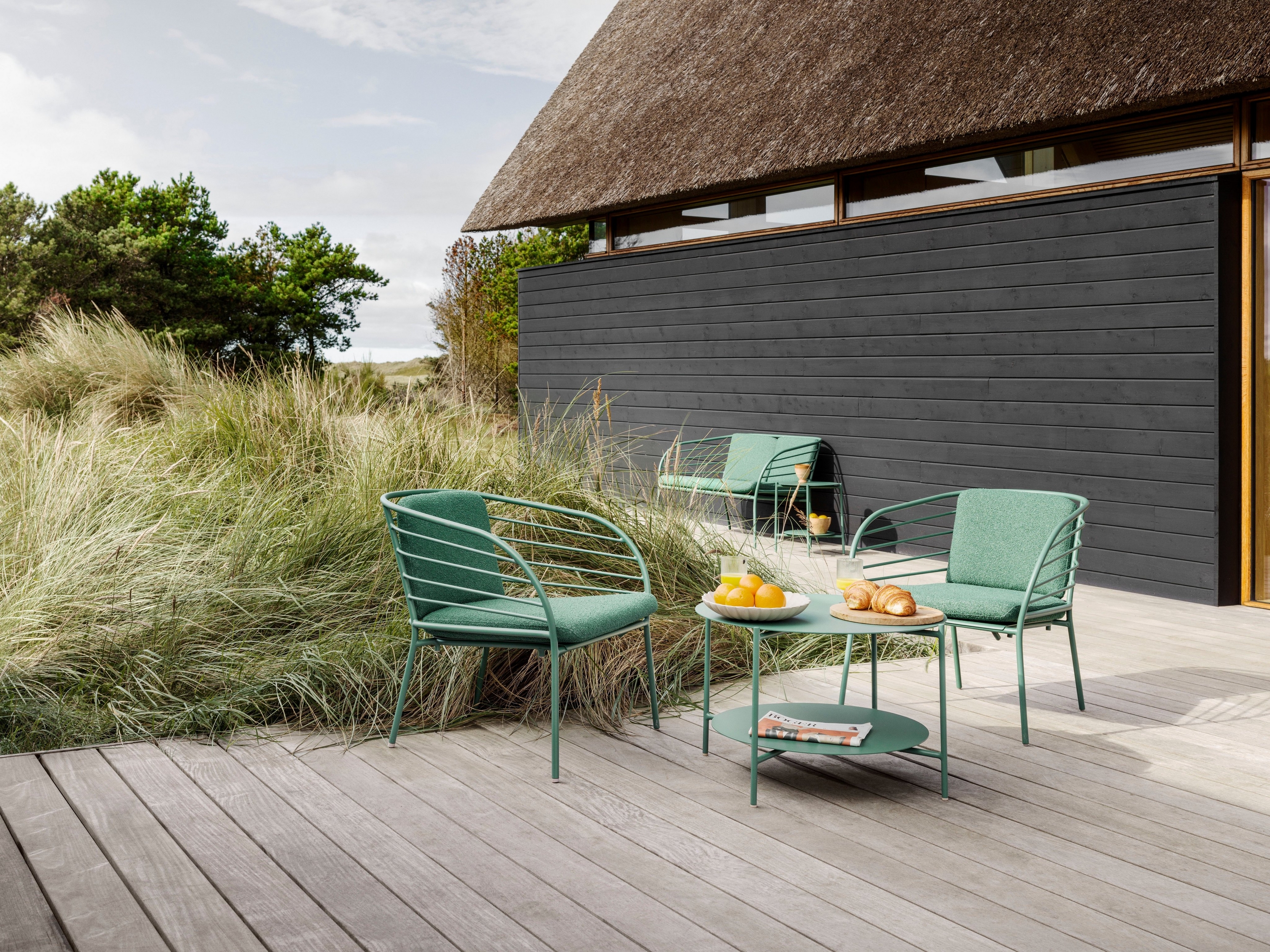 The back deck of a Danish summer home with the Cancún side table lounge chairs in matt green.
