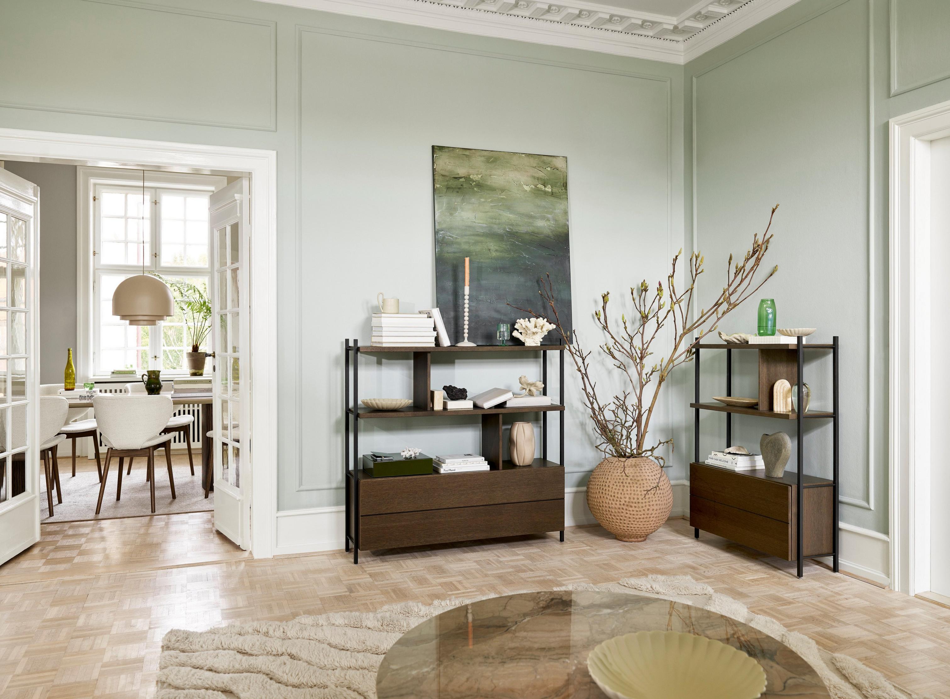 Classic room with pastel walls, shelving units, decorative items, and a view into an adjoining space.