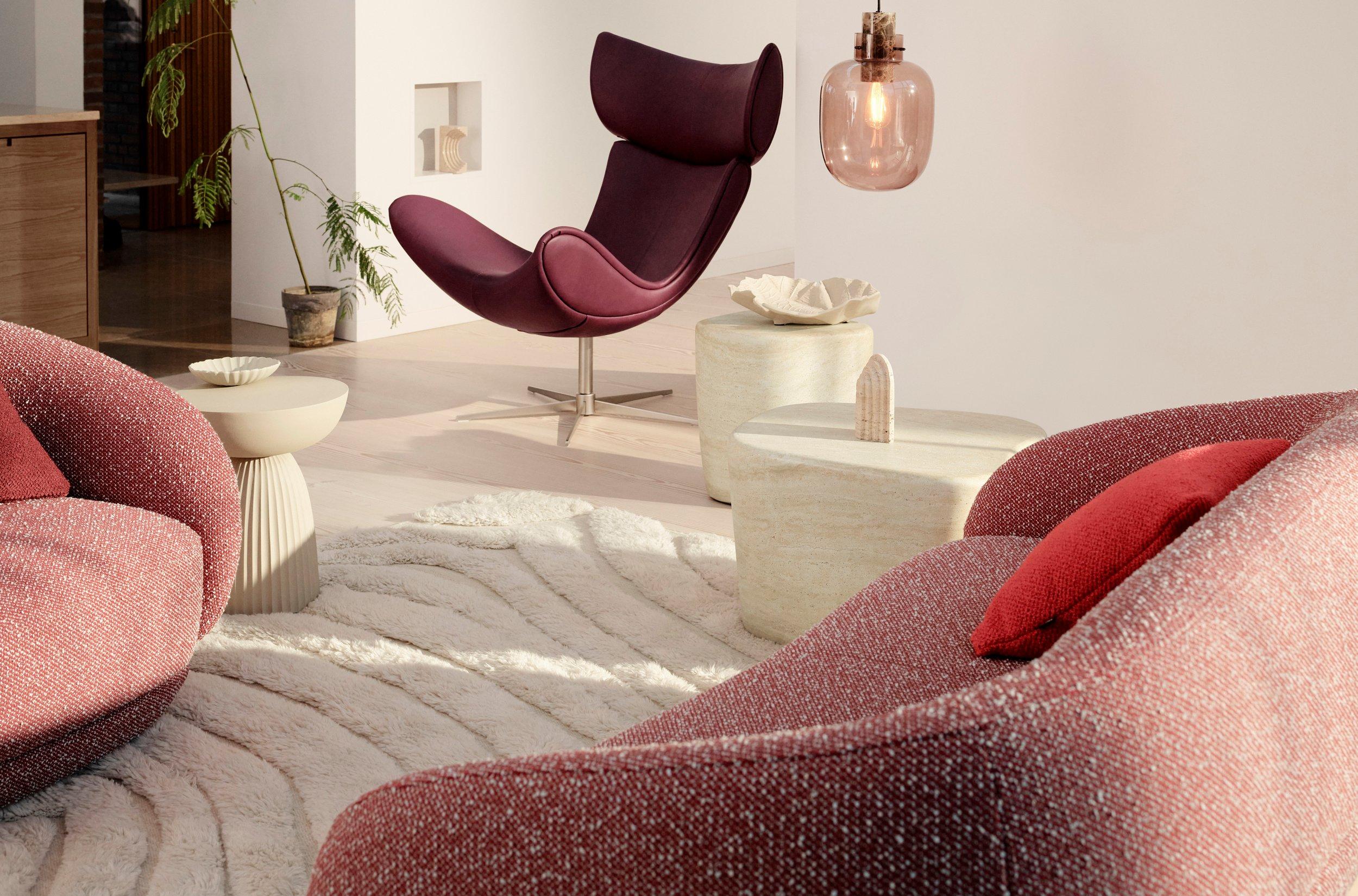 Image of living room with BoConcept Imola armchair in burgundy leather, plus the Bolzano 2.5 seater sofa in red Avellino fabric, Bolzano swivel armchair in red Avellino fabric, Expose side table, Eden pouffe and Tivoli coffee table