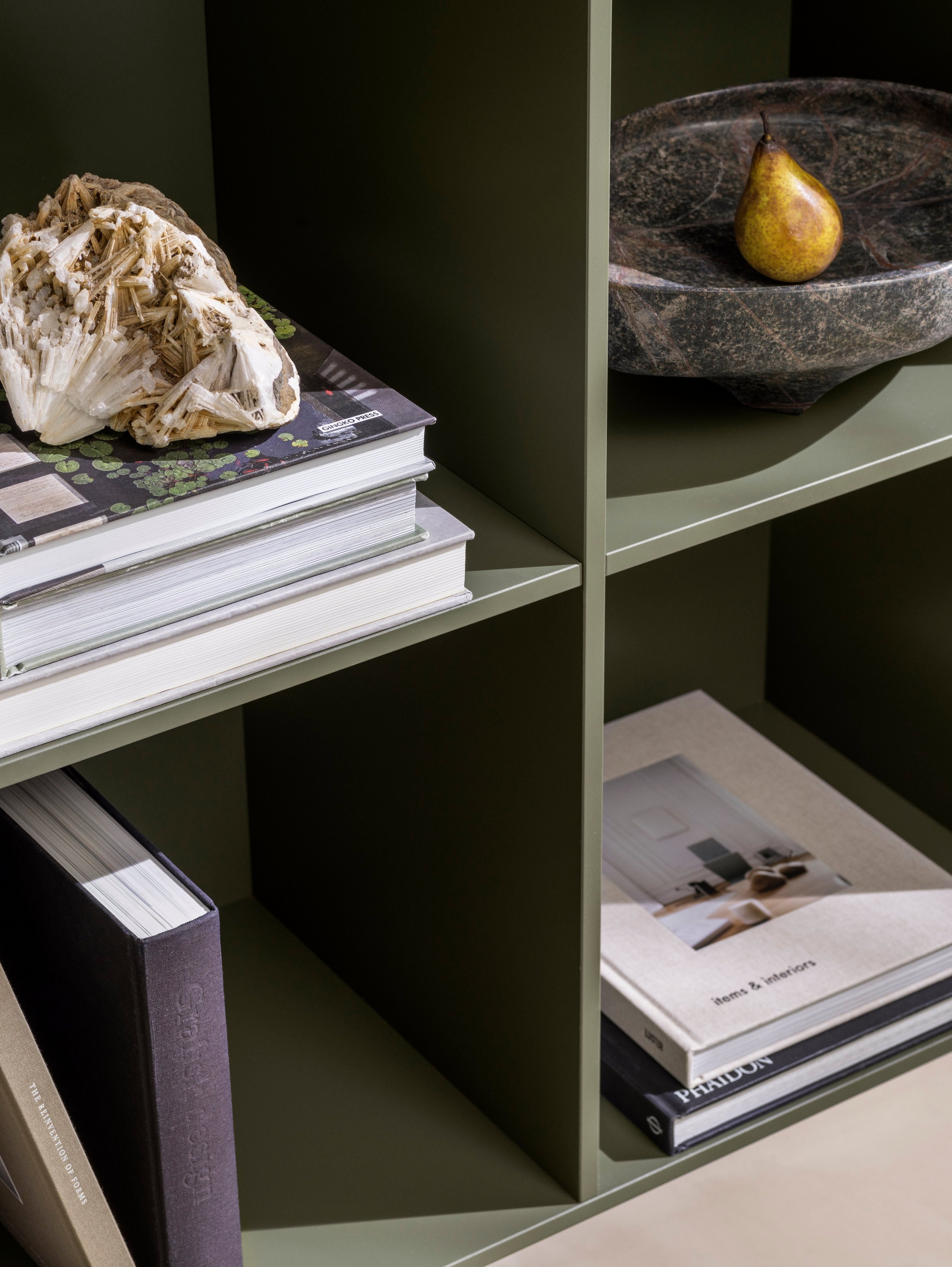 Bliższe spojrzenie na półkę na książki Como w matowym lakierze w kolorze zgaszonej zieleni.
