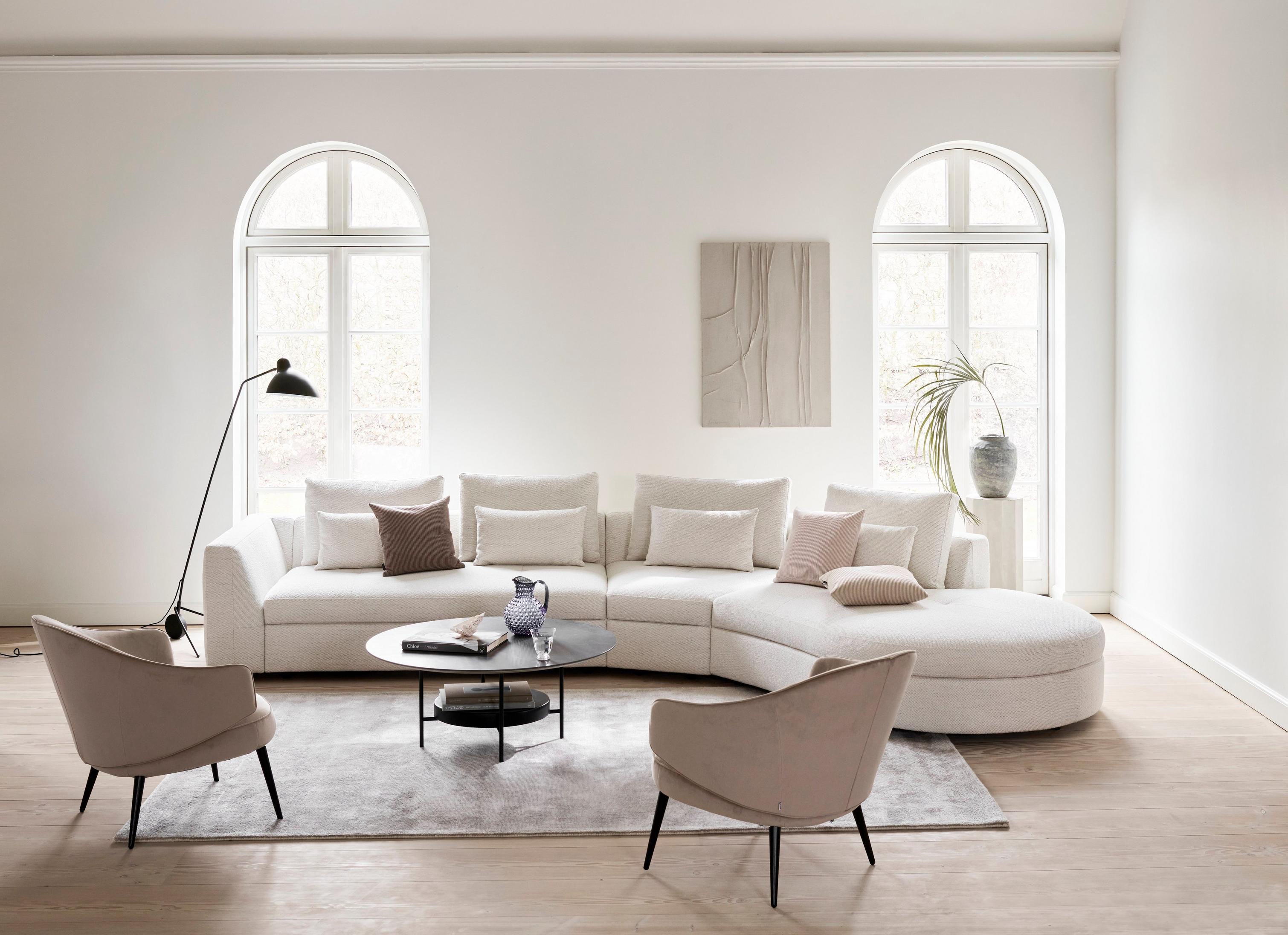 O sofá Bergamo com módulo relax redondo em tecido Lazio, com a mesa de apoio Madrid com revestimento de cerâmica em mármore escuro.