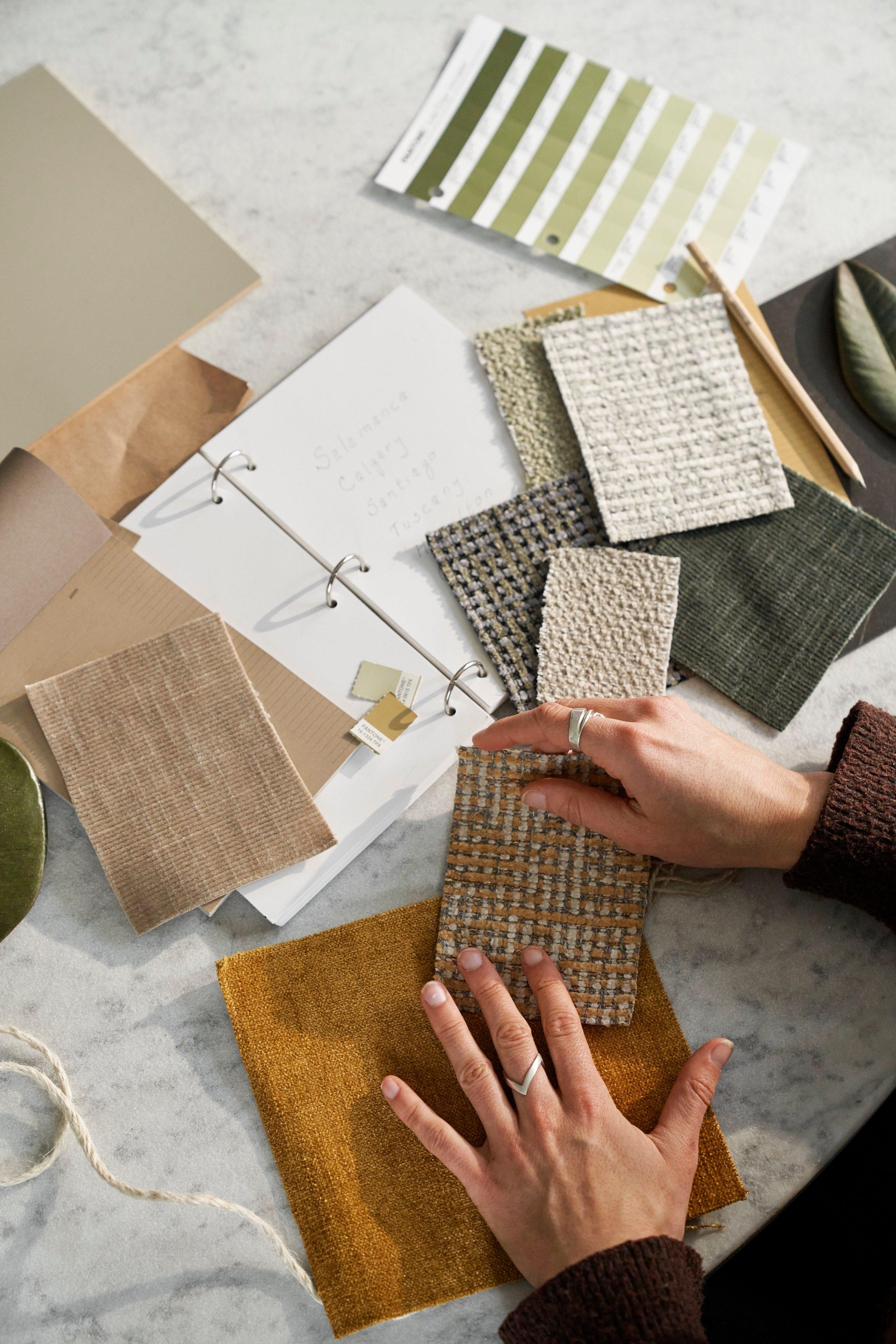Person looking through fabric swatches on a ceramic table.