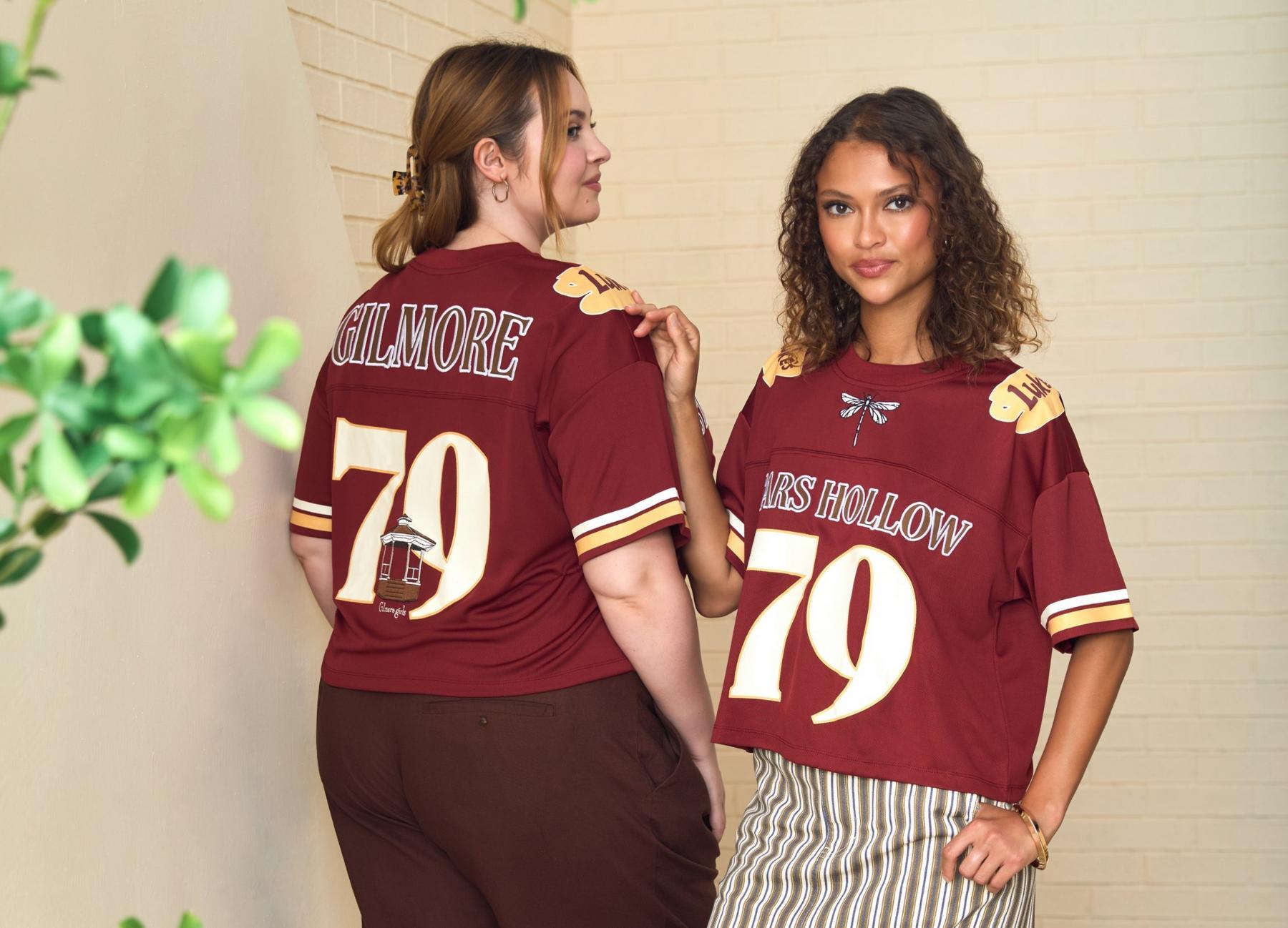 Two models wearing maroon jersey tops with “Stars Hollow 79” graphic as the front view and “Gilmore 79” graphic as the back view. Shop Now.