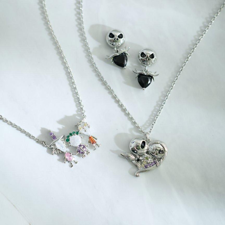 Two silver necklaces and matching earrings with skeleton faces and black heart charms. Shop Now.