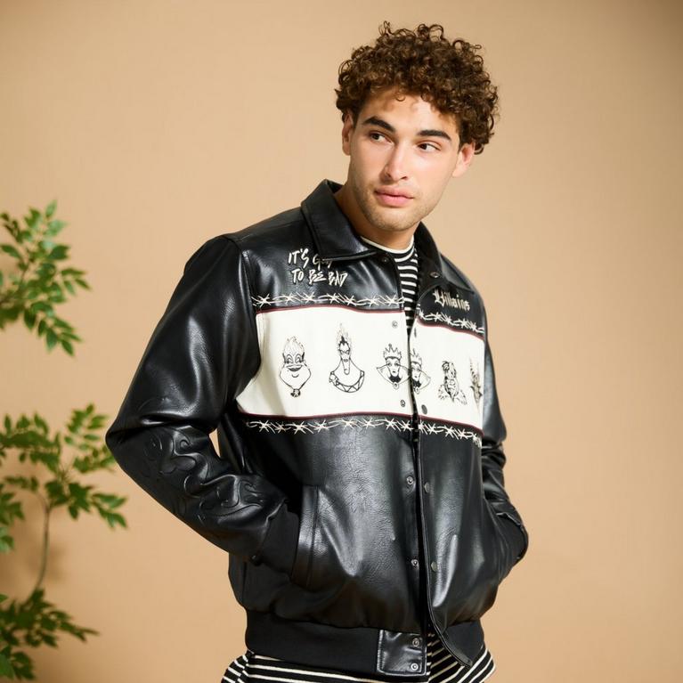 Man modeling black faux leather jacket with white panel and villain sketches, hands in pockets. Shop Now.