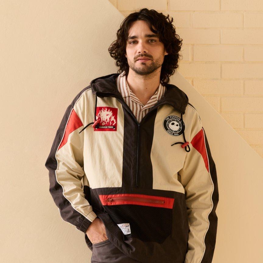 Model wearing a color-blocked half-zip pullover jacket with patches and a front zip pocket. Shop Now.