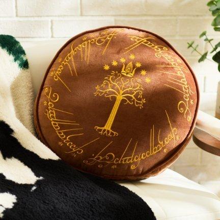 Round brown pillow with gold tree and script design.