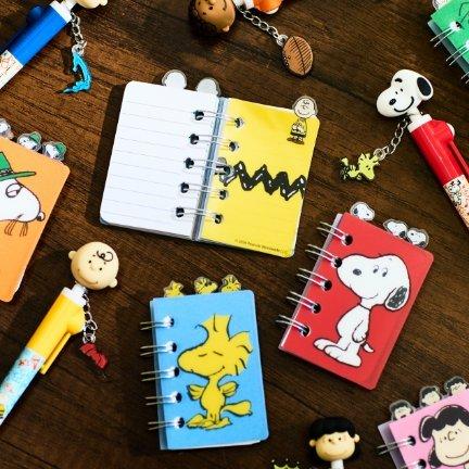 Peanuts-themed mini spiral notebooks and character keychains on a tabletop.