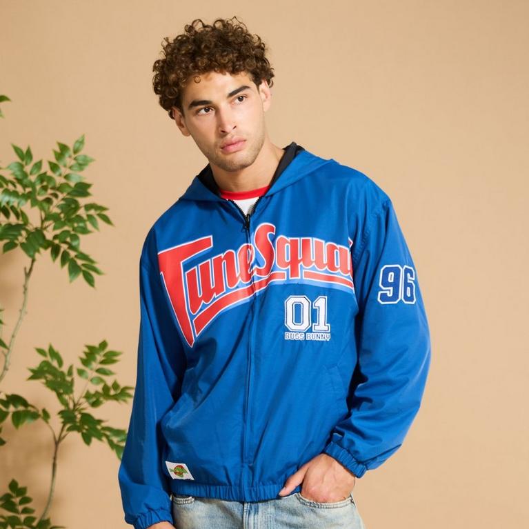 Model wearing a blue Tune Squad zip-up hooded jacket with Bugs Bunny 01 and 96 patches. Shop Now.