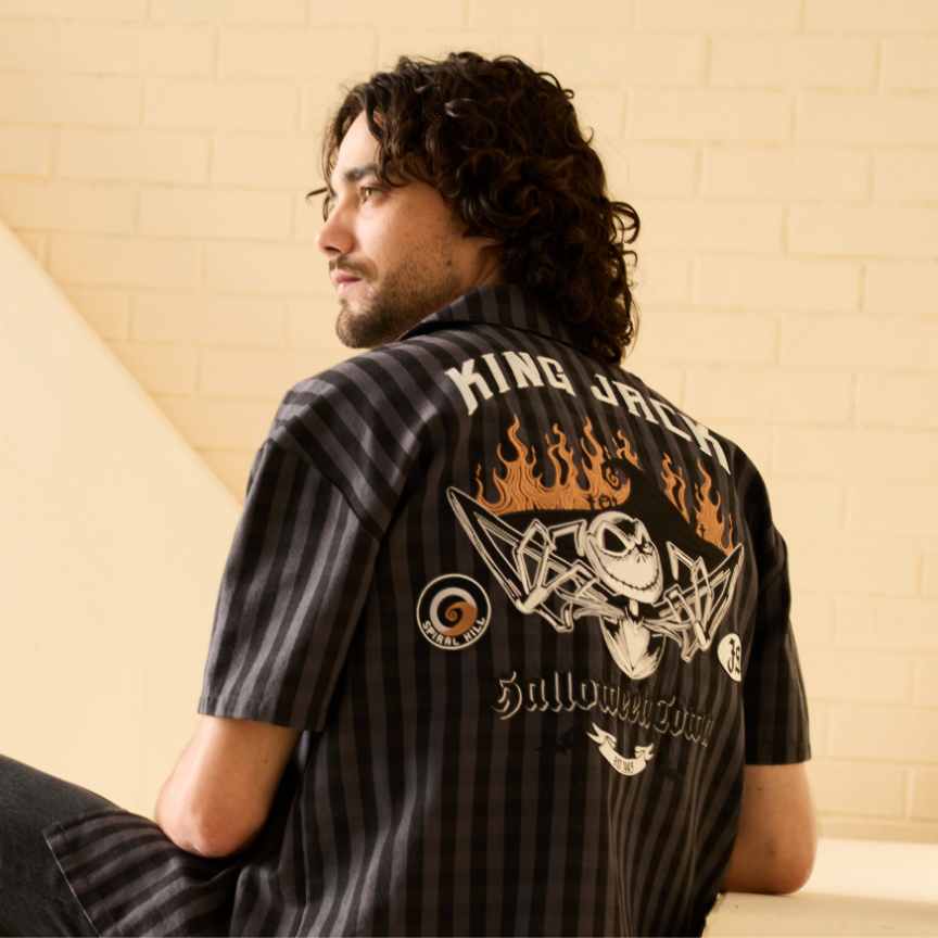 Man wearing black striped button up shirt with “KING JACK” and flame graphic on back. Shop Now.