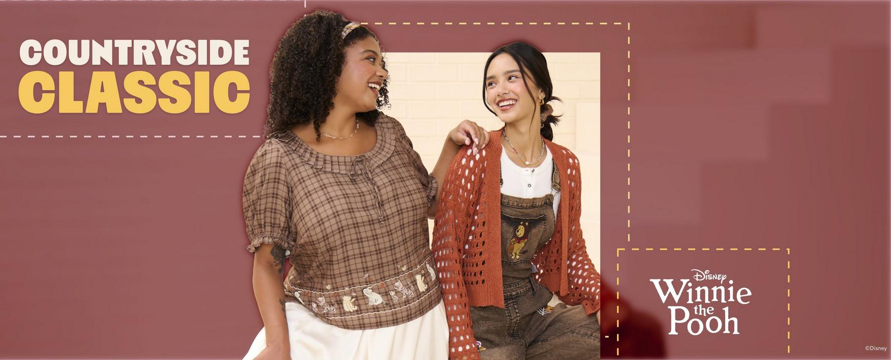 Two models in countryside-style outfits; one wears Disney Winnie the Pooh overalls and other wear a Winnie the Pooh top. Shop Now.