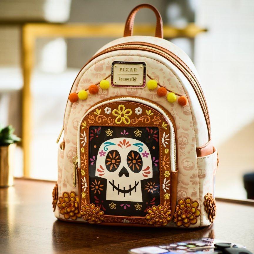 Pixar Coco Loungefly mini backpack with embroidered skull detailing and pom-pom trim along the top. Shop Now.