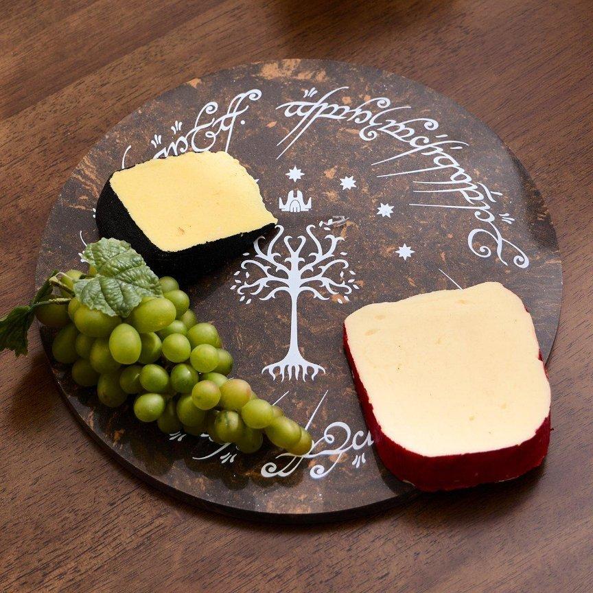 Two cheese wedges and a bunch of green grapes on a round Lord of the Rings Tree of Gondor marble serving board. Shop Now.