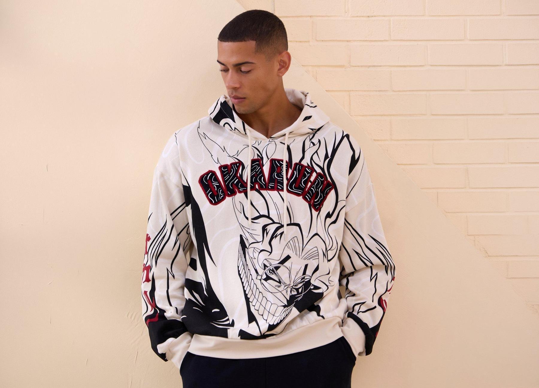 Model wearing a white hoodie with red Okarun lettering and anime character print. Shop Now.