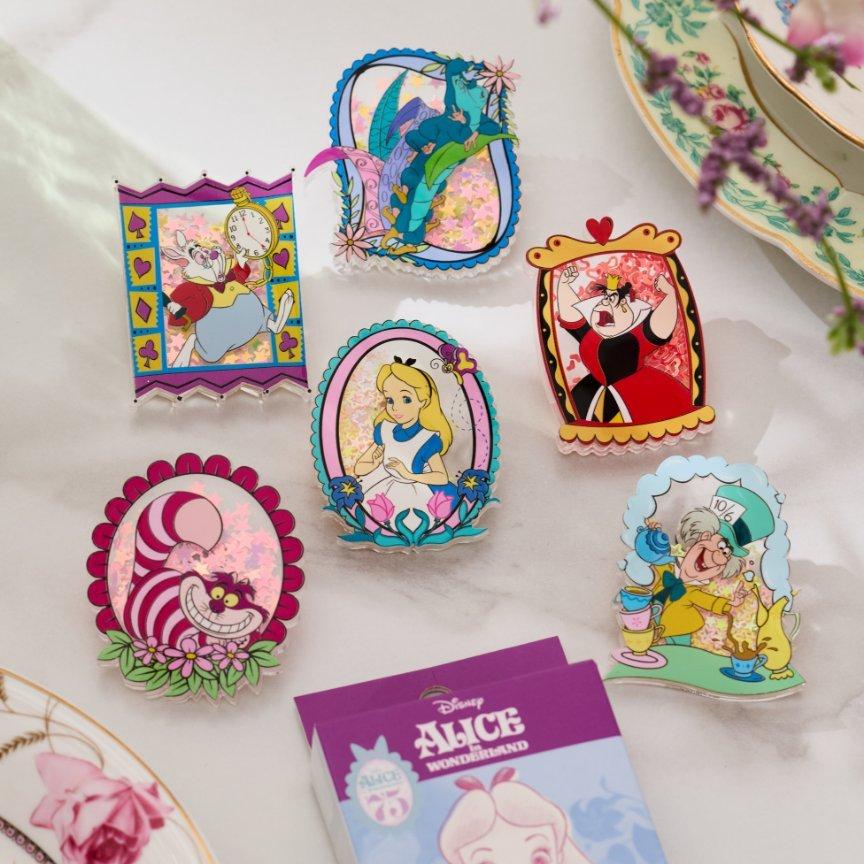 Six Disney Alice in Wonderland character pins displayed on a tabletop. Shop Now.