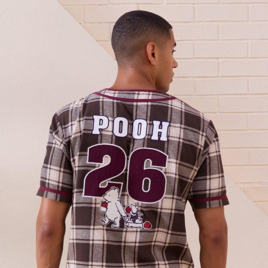 Man wearing plaid jersey with “POOH” and number 26 graphic on back. Shop Now.