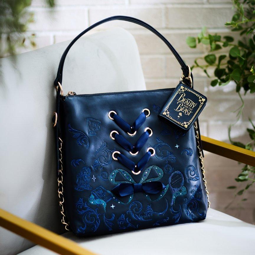 Navy Beauty and the Beast handbag with lace-up front, bow detail, and gold chain strap. Shop Now.