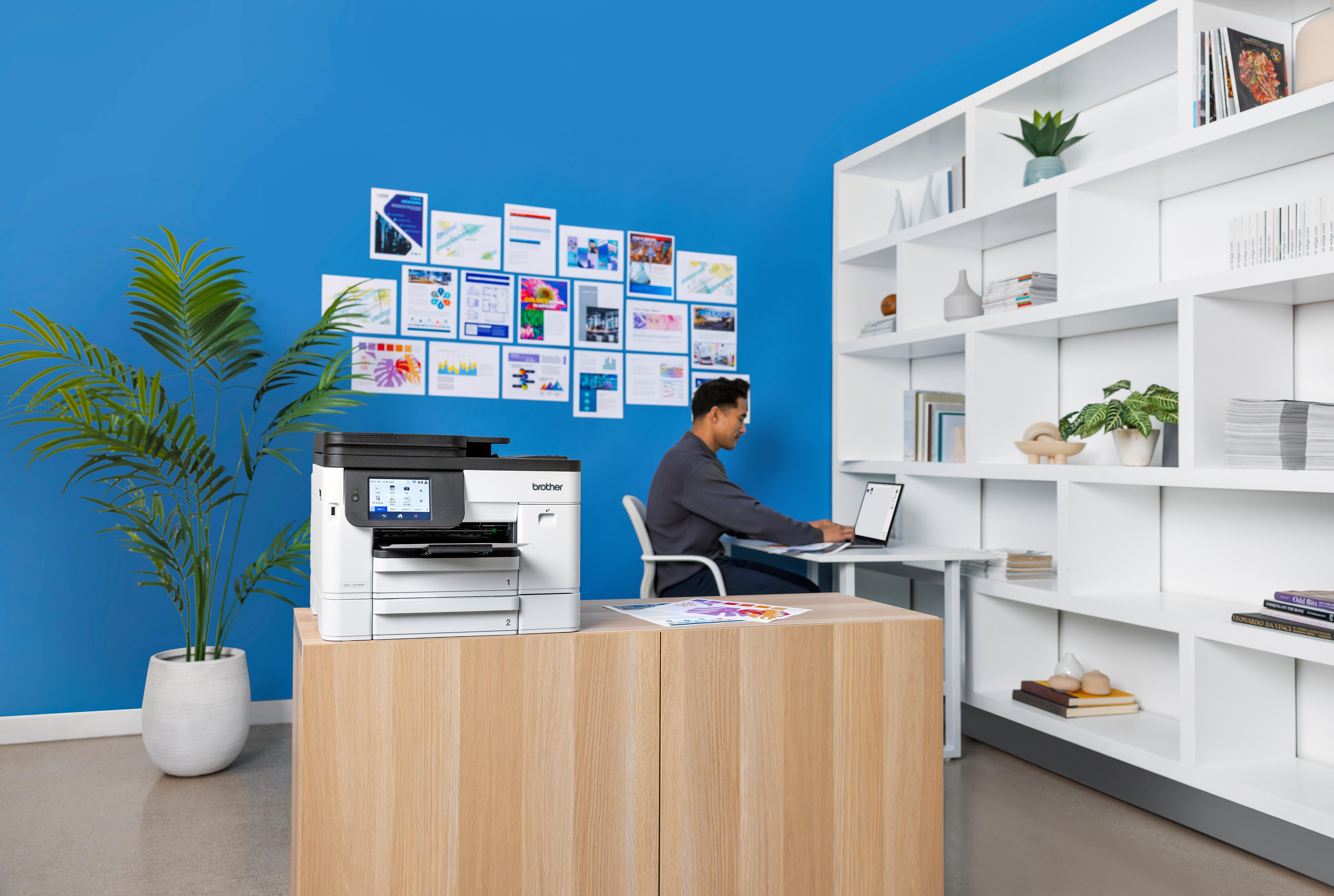 Person placing a color document into a multifunction printer in a modern office.