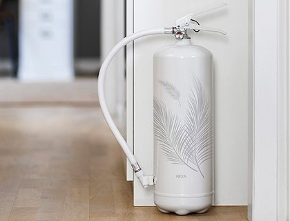 En vit brandsläckare står längs en vägg