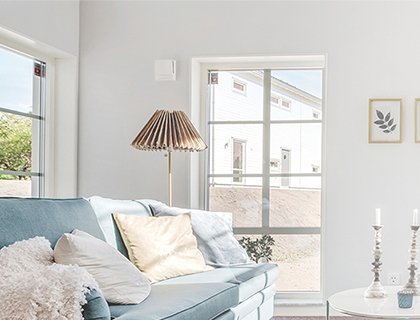 ett vardagsrum med en soffa, en golvlampa. Rummet har ett stort fönster.
