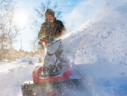 En snöslunga sprutar stora mängder snö i ett vinterlandskap