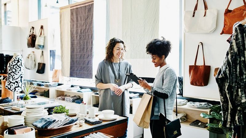 Two women in a shop smiling whilst looking at something