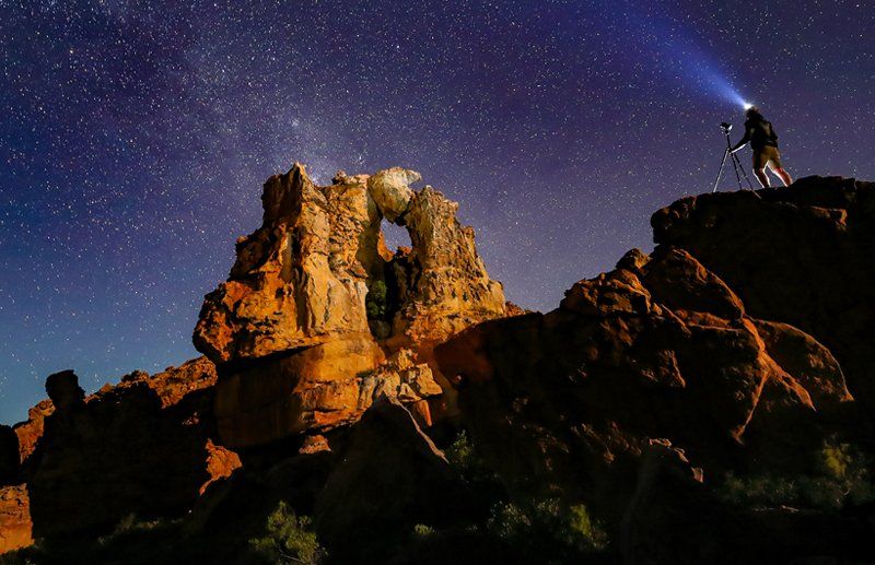 Image of the night sky showing the stars and a photographer taking pictures of the night sky