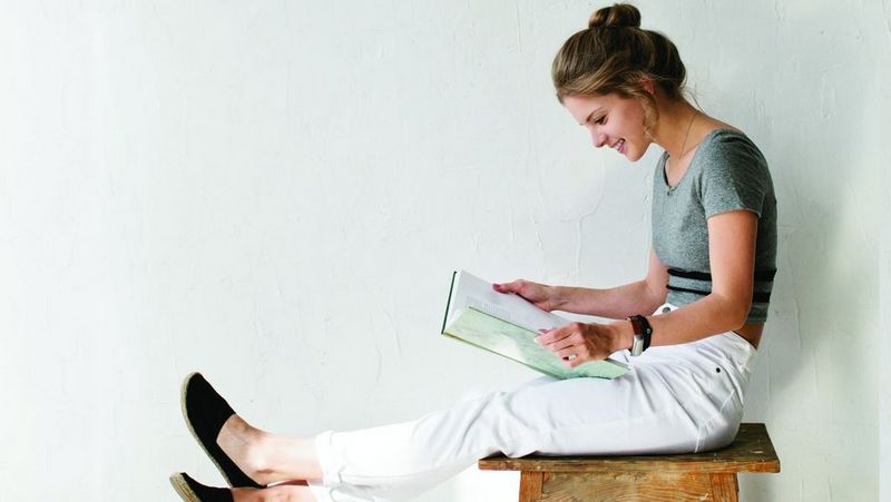 Young woman reading book on stool
