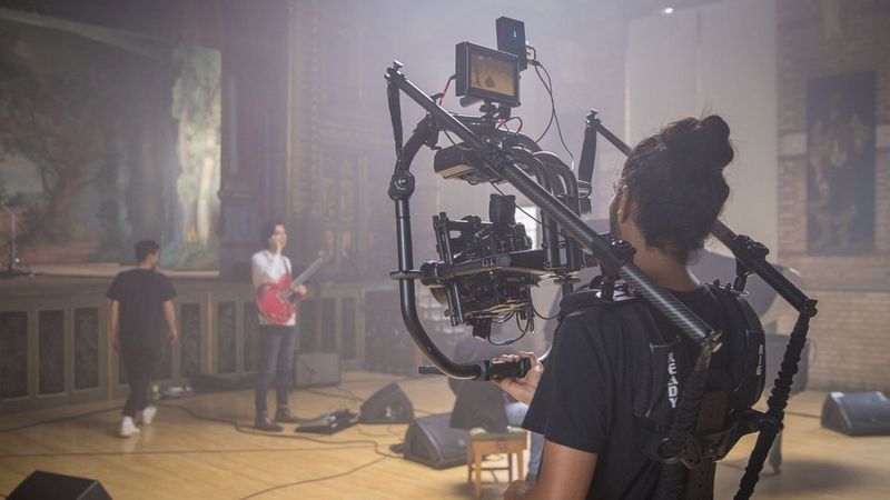 Man with guitar being filmed