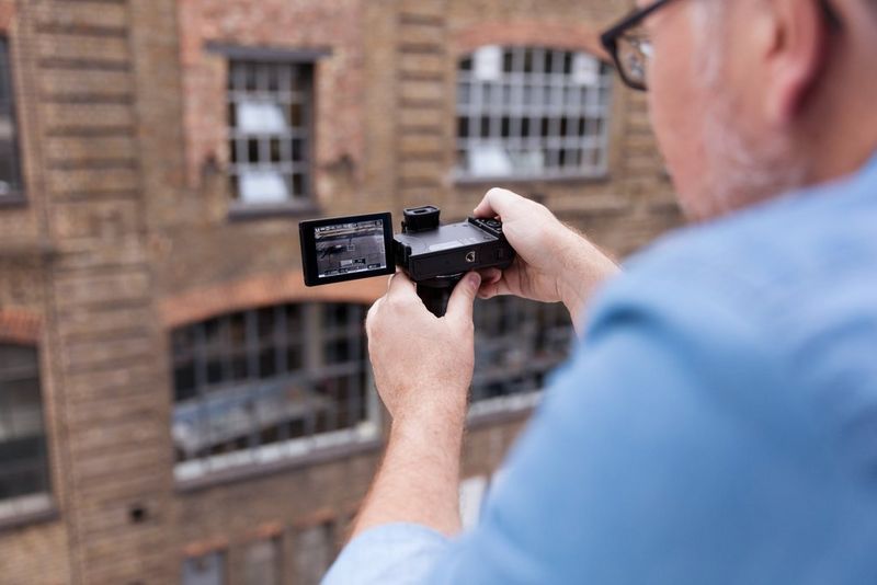 Canon PowerShot G5 X Mann, der ein Foto mit ausgeklapptem Blitz und Bildschirm aufnimmt