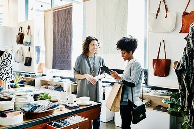 Two women in a shop smiling whilst looking at something