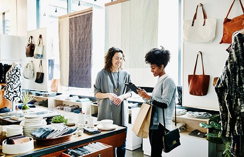 Two women in a shop smiling whilst looking at something