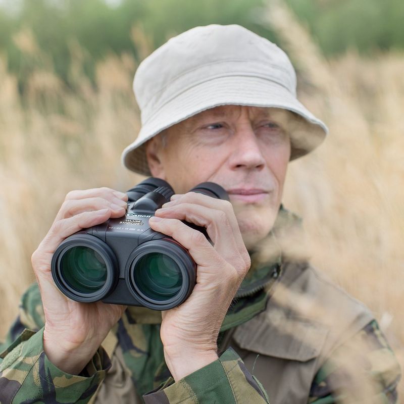 Canon 10x42L IS WP Fernglas Mann, der das Fernglas in einem Feld in der Hand hält
