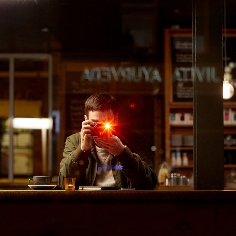 Canon EOS M6 + EF-M 18-150mm IS STM- Objektiv Schwarz 0 Ein Mann beim Aufnehmen eines Fotos in einem dunklen Café