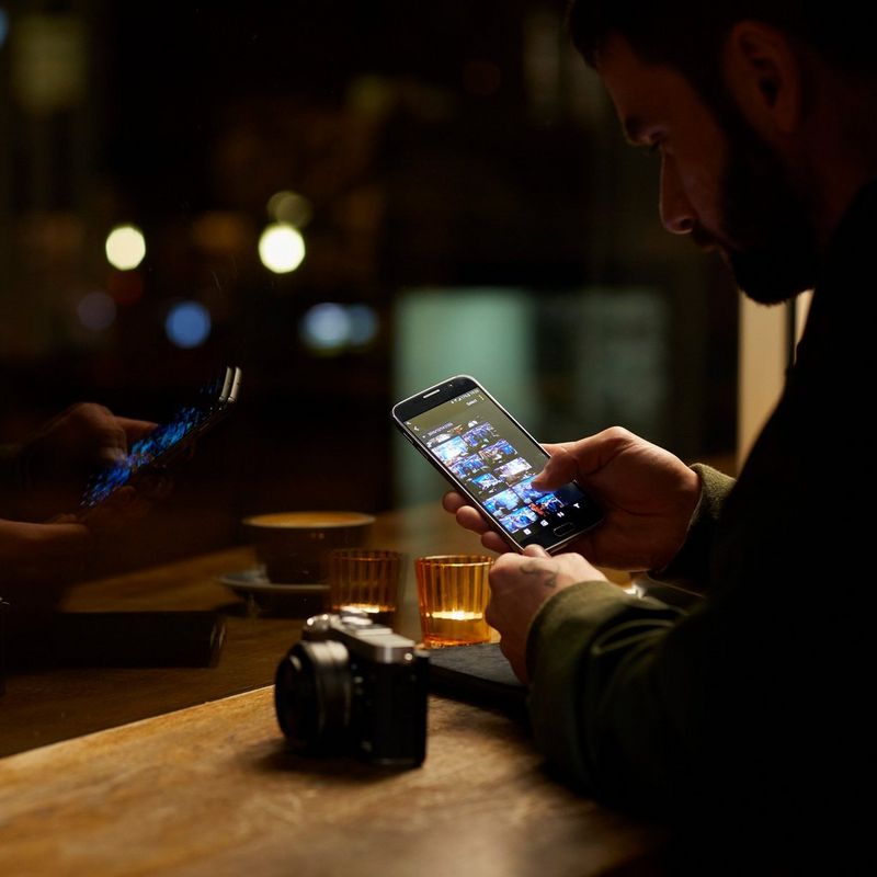 Canon EOS M6 + EF-M 15-45mm IS STM Objektiv Schwarz 0 Ein Mann beim Durchsehen der Bilder auf seinem Smartphone