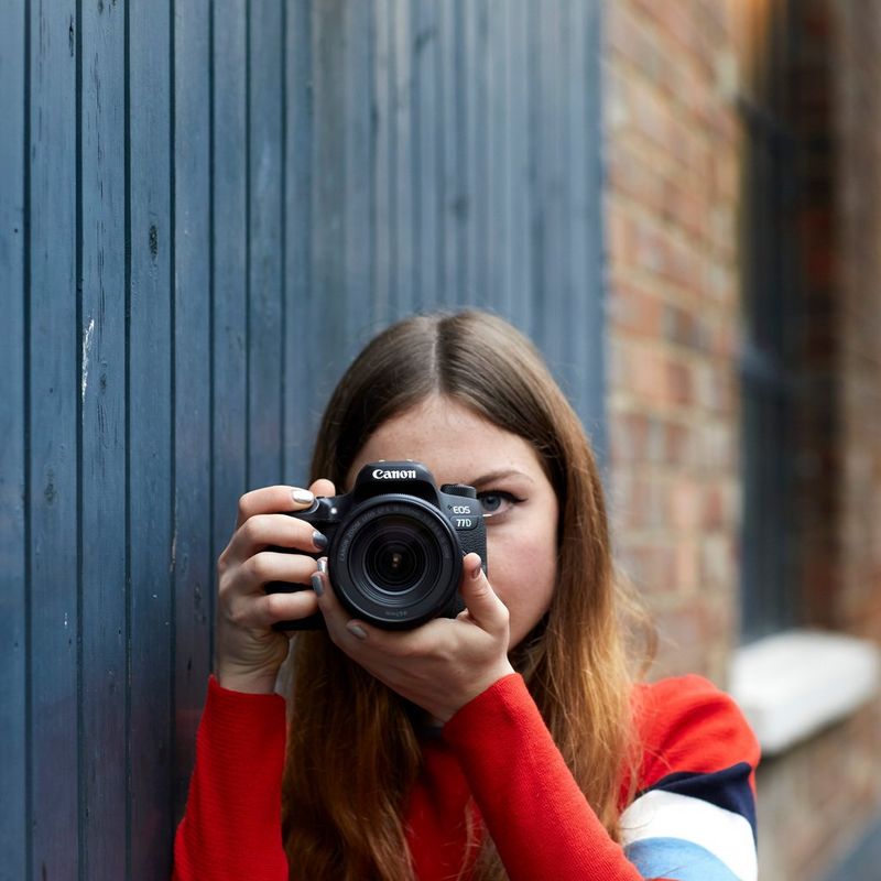 Canon EOS 77D + EF 18-55mm IS STM Objektiv + Rucksack + Ersatzakku Frau, die eine Kamera hält und Bilder aufnimmt