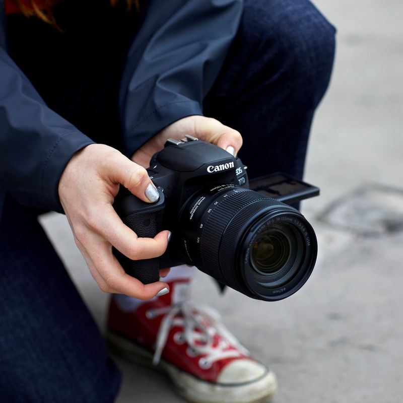 Canon EOS 77D + EF 18-55mm IS STM Objektiv + Rucksack + Ersatzakku Halten der Kamera mit zwei Händen und Aufnehmen eines Fotos