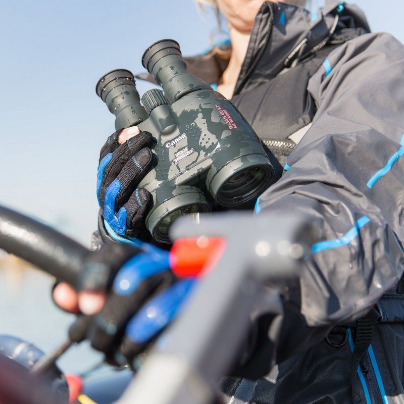 Canon 18x50 IS AW Allwetter-Fernglas Frau, die ein Fernglas in der Hand hält, auf dem Regentropfen illustrieren, dass es wasserdicht ist