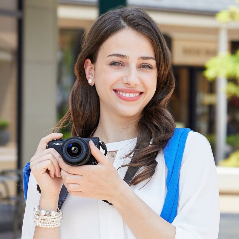 Canon EOS M100 Schwarz + Canon EF-M 15-45mm f/3.5-6.3 IS STM Objektiv Schwarz 0 Eine Hand, die die Kamera hochhebt