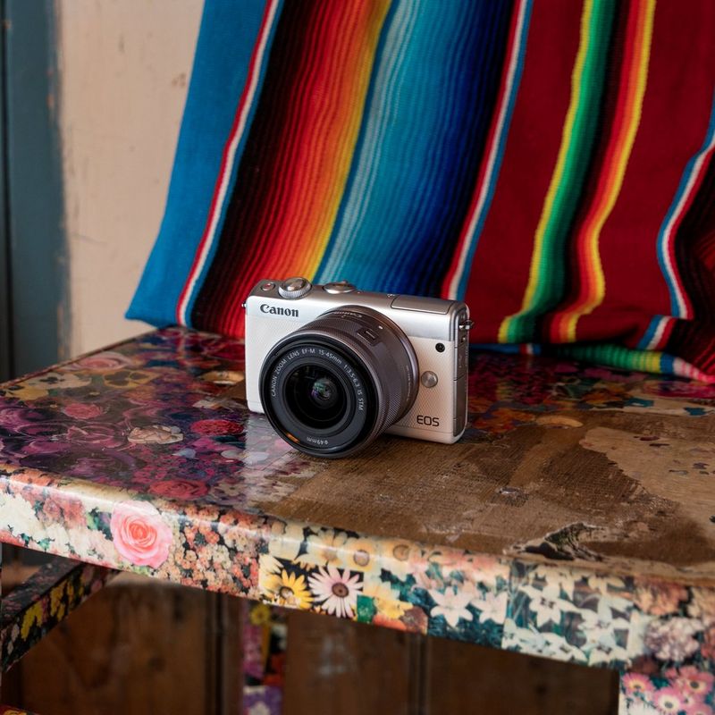 Canon EOS M100 Weiß + EF-M 15-45mm f/3.5-6.3 IS STM Objektiv Silber 0 Die Kamera auf einem Stuhl