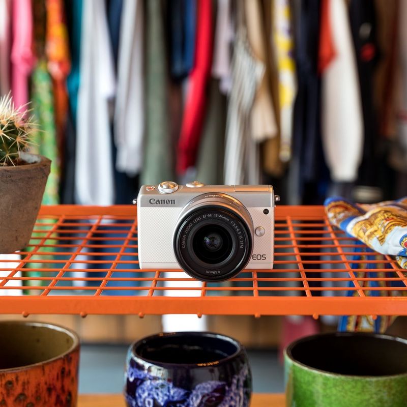 Canon EOS M100 Weiß + EF-M 15-45mm f/3.5-6.3 IS STM Objektiv Silber 0 Die Kamera auf einem Regal