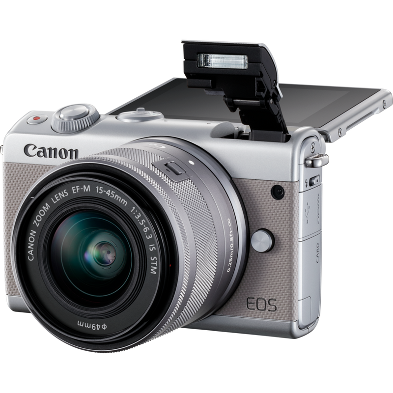 Canon EOS M100 Grau + EF-M 15-45mm f/3.5-6.3 IS STM Objektiv Silber Produkt Diagonale Ansicht mit internem Blitz und klappbarem Display