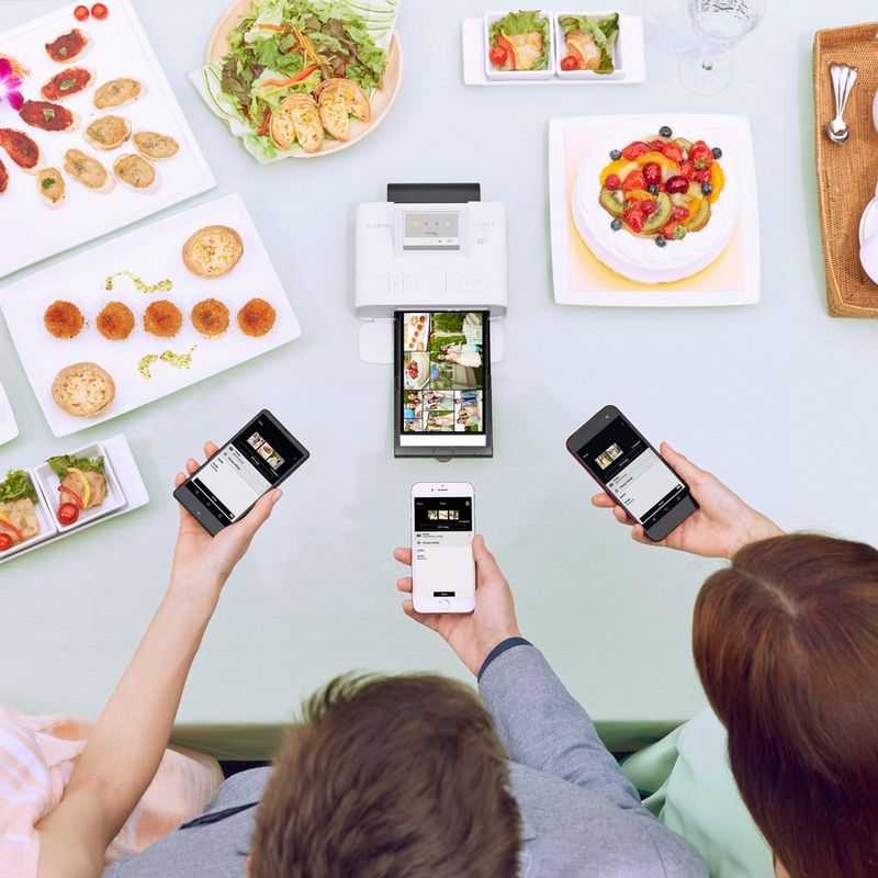 Canon SELPHY CP1300 – Schwarz 3 Personen benutzen den Drucker, im Hintergrund stehen Teller