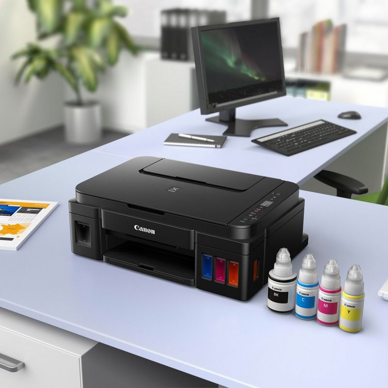 Canon PIXMA G2510 Drucker Auf einem Bürotisch zusammen mit den Tintenflaschen