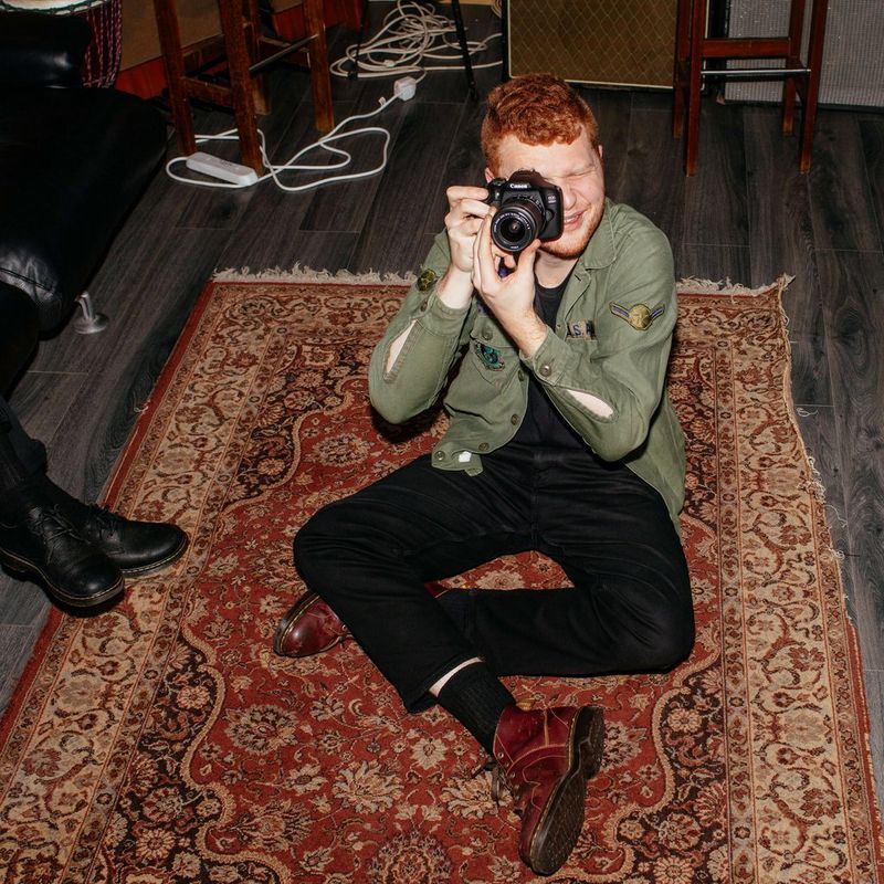 Canon EOS 2000D + EF-S 18-55mm IS II Objektiv + Rucksack + SD-Karte Mann, der die Kamera hält, mit Vorderansicht des Produkts