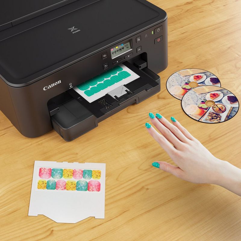 Canon PIXMA TS705 Tintenstrahldrucker Produkt Vorderansicht mit einer Person, die versucht, das Foto zu entnehmen