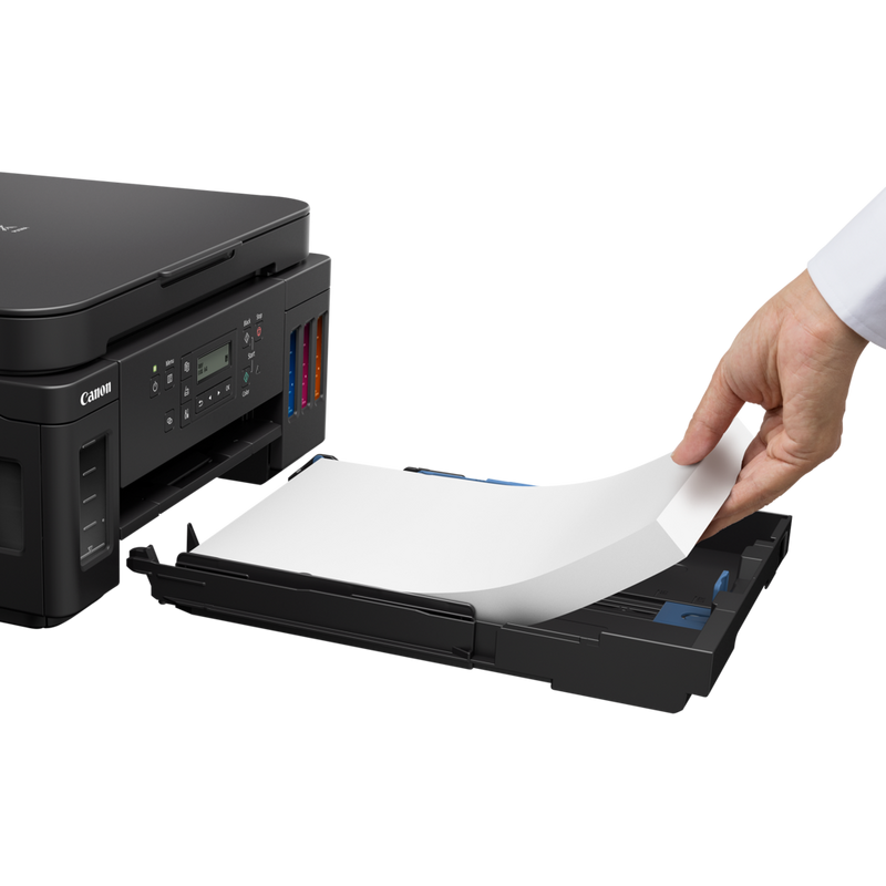 Canon PIXMA G6050 3-in-1 MegaTank Drucker mit nachfüllbaren Tintenbehältern Produkt Schrägansicht mit einer Person, die dem Papiereinzug Papier hinzufügt
