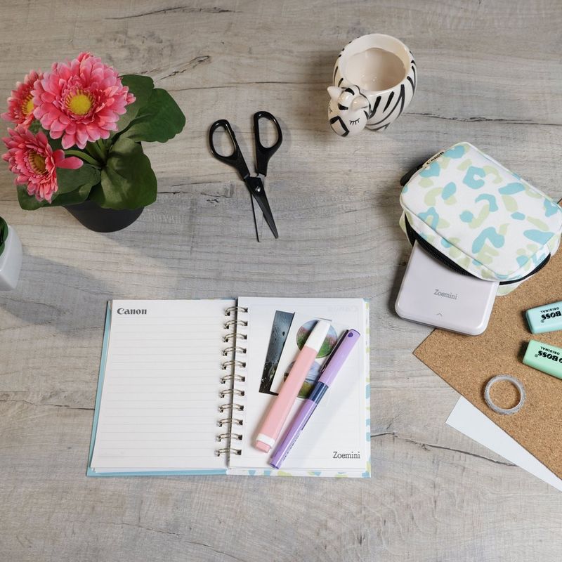 Canon Zoemini Mini-Fotodrucker, weiß + Tagebuch + Tasche Drucker auf einem Schreibtisch mit Scheren