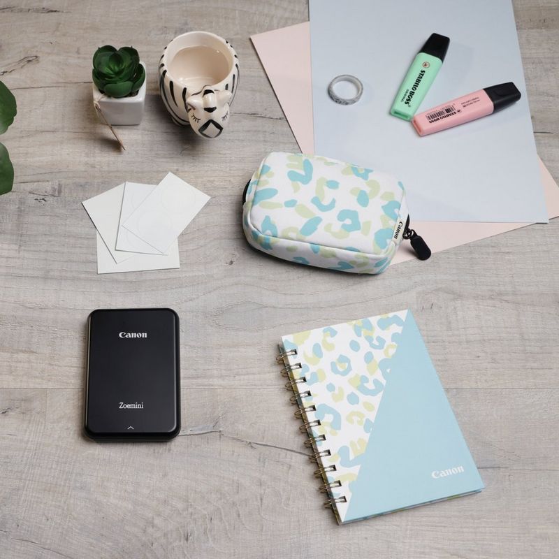 Canon Zoemini Mini-Fotodrucker, Schwarz + Tagebuch + Tasche Drucker auf einem Schreibtisch mit Tasse