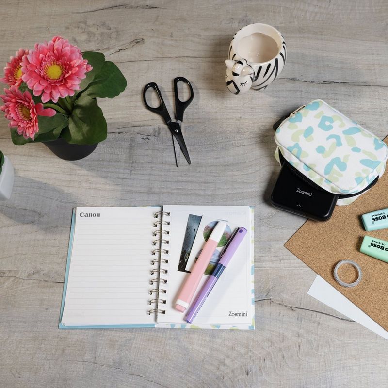 Canon Zoemini Mini-Fotodrucker, Schwarz + Tagebuch + Tasche Drucker auf einem Schreibtisch mit Scheren